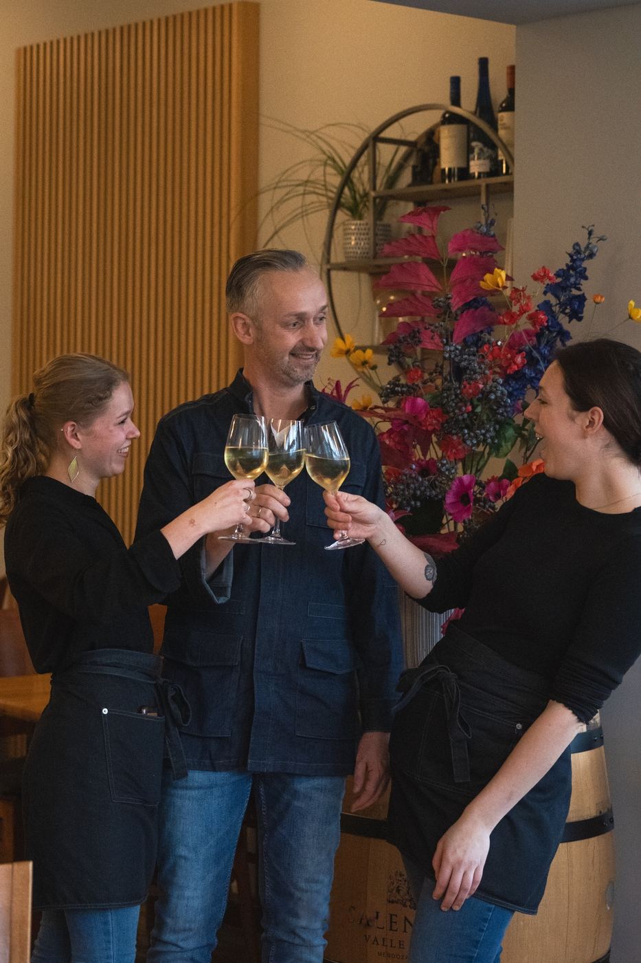 Zo gaat het tijdens een shoot: drie mensen proosten lachend met een glas wijn